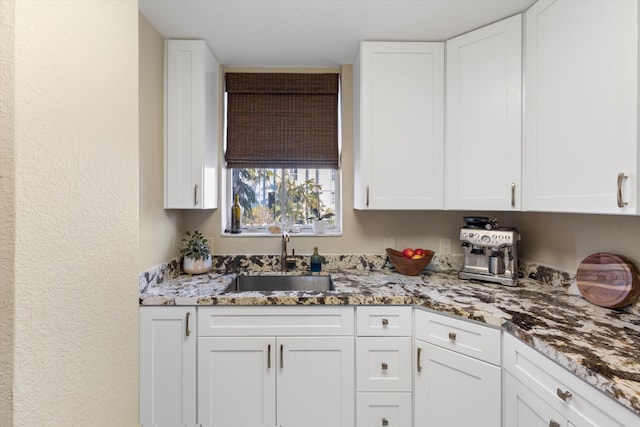 64 Seaside N Ct, Key West, FL 33040 - kitchen featuring a sink, white cabinets, light stone countertops, and a textured wall
