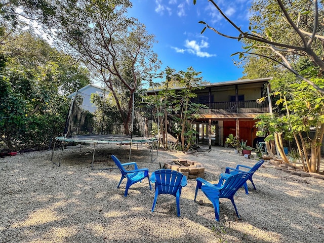 view of yard with an outdoor fire pit and a trampoline