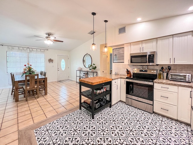 kitchen with light tile patterned floors, hanging light fixtures, backsplash, stainless steel appliances, and white cabinets