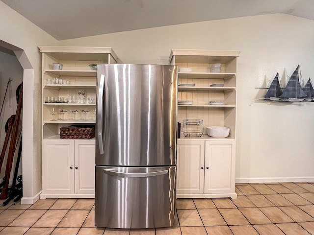 kitchen featuring vaulted ceiling, built in features, stainless steel refrigerator, and light tile patterned flooring