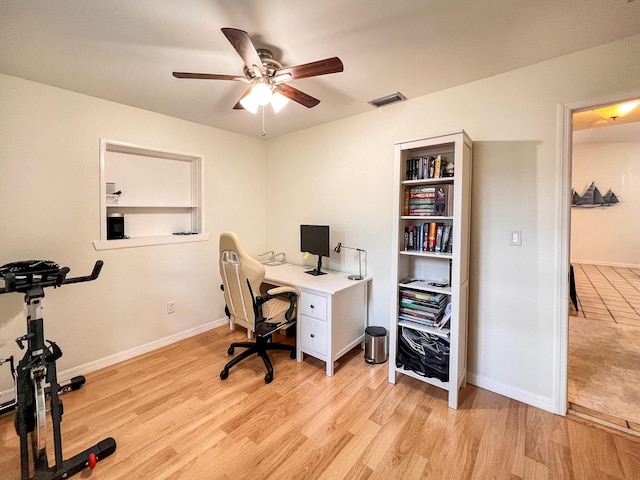 office space featuring ceiling fan, light wood-type flooring, and built in shelves