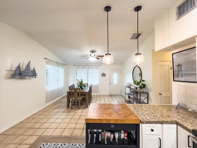 kitchen featuring lofted ceiling, hanging light fixtures, light tile patterned floors, beverage cooler, and white cabinets