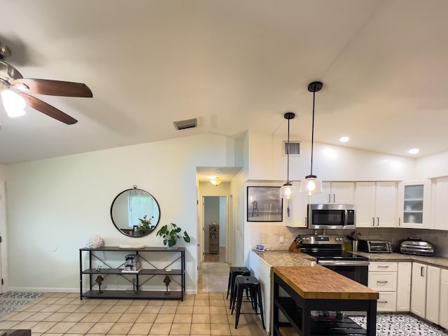 kitchen featuring appliances with stainless steel finishes, backsplash, white cabinets, decorative light fixtures, and vaulted ceiling