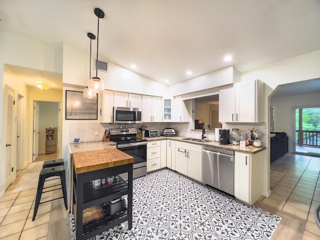 kitchen with pendant lighting, white cabinetry, sink, backsplash, and stainless steel appliances