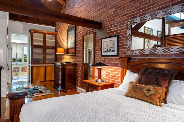 bedroom featuring brick ceiling, brick wall, dark hardwood / wood-style floors, and beam ceiling