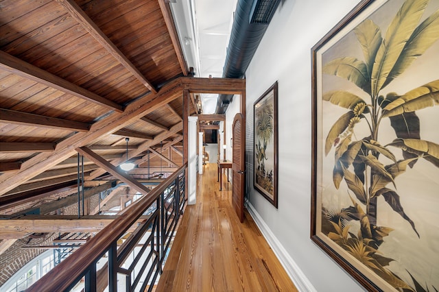 hall featuring beam ceiling, light hardwood / wood-style floors, and wooden ceiling