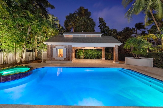 view of swimming pool featuring an outbuilding, an in ground hot tub, and a patio area