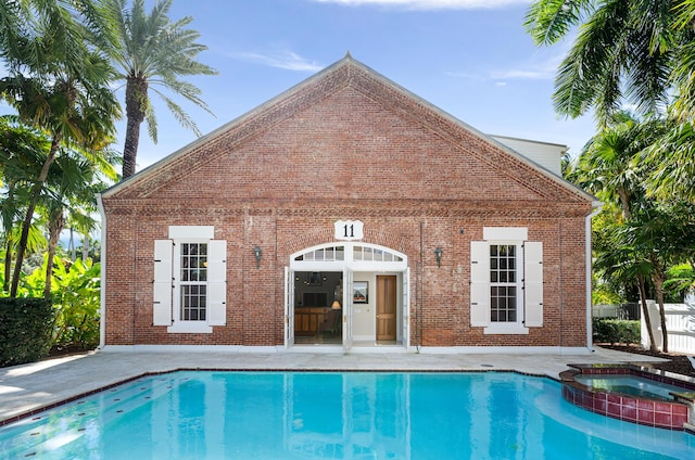 view of pool with an in ground hot tub and an outbuilding