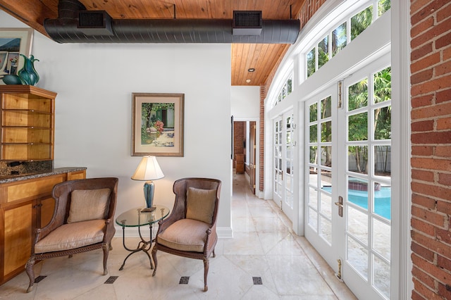 sitting room featuring brick wall and wooden ceiling