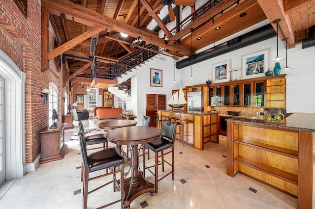 dining area with a towering ceiling and brick wall