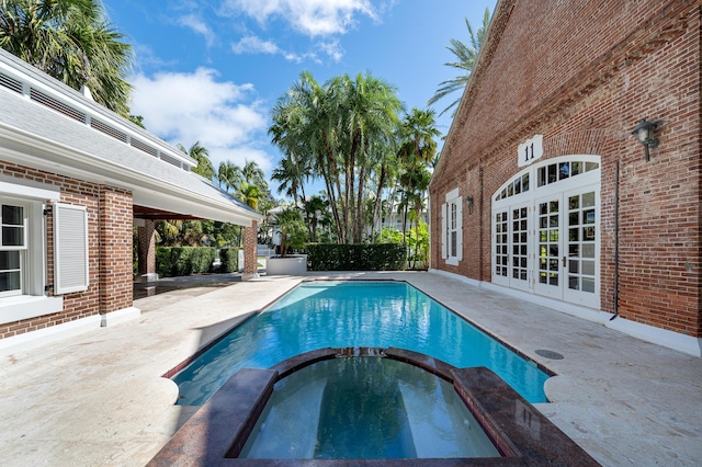 view of pool with french doors, an in ground hot tub, and a patio area