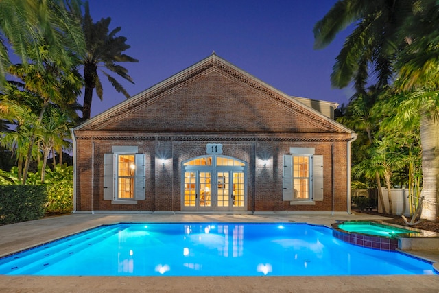 view of swimming pool with an outbuilding, an in ground hot tub, a patio area, and french doors