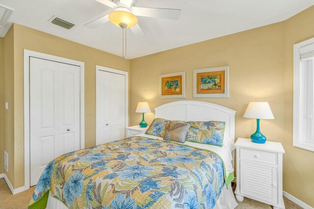 bedroom with multiple closets, visible vents, a ceiling fan, carpet flooring, and baseboards