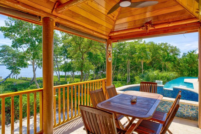 deck with a ceiling fan, outdoor dining space, a water view, and a gazebo