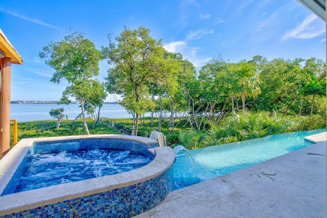 view of swimming pool featuring an in ground hot tub and a water view