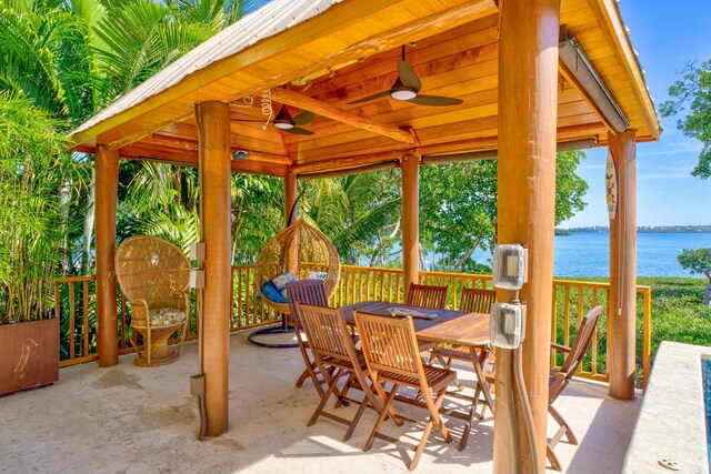 view of patio featuring outdoor dining area, a water view, and a ceiling fan