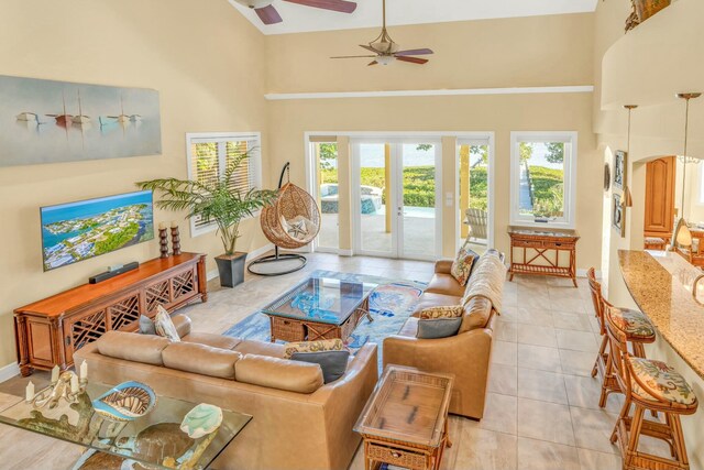 living area featuring arched walkways, french doors, a towering ceiling, and baseboards