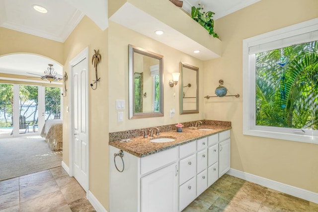 full bathroom with double vanity, a ceiling fan, baseboards, and a sink