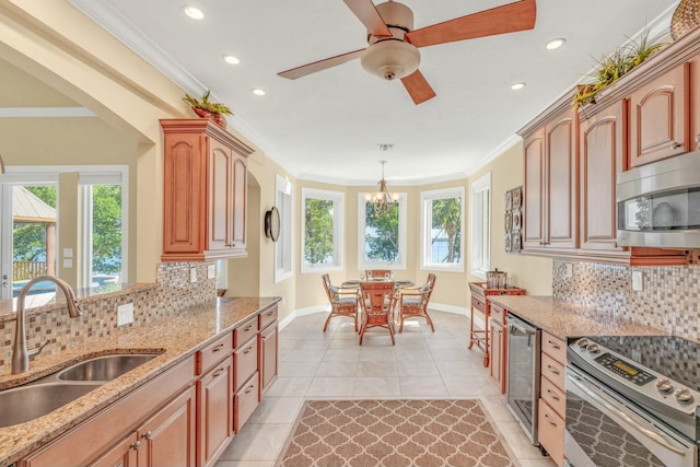 kitchen featuring wine cooler, appliances with stainless steel finishes, light stone counters, ornamental molding, and a sink