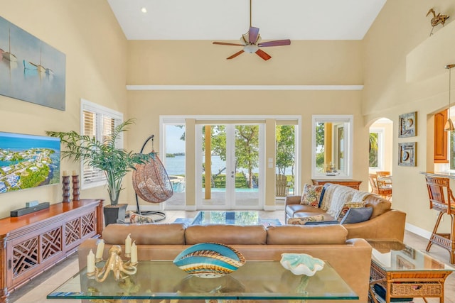 tiled living area with a ceiling fan, arched walkways, french doors, and a high ceiling