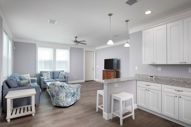 kitchen with decorative light fixtures, white cabinetry, a kitchen breakfast bar, ornamental molding, and kitchen peninsula