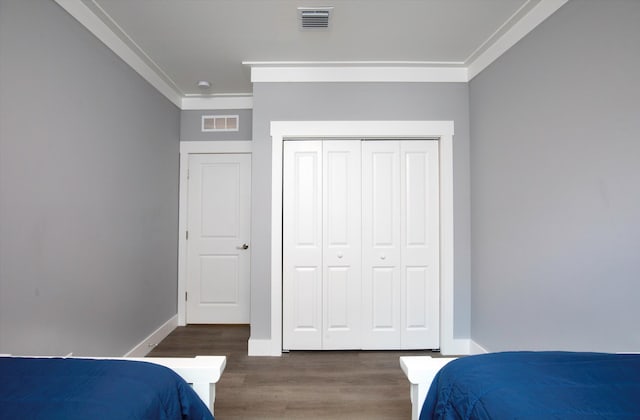 bedroom with ornamental molding, dark hardwood / wood-style floors, and a closet