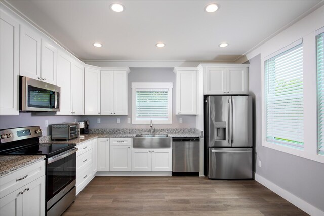 kitchen with sink, stainless steel appliances, light stone countertops, light hardwood / wood-style floors, and white cabinets