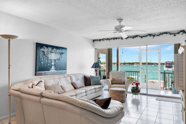 living room featuring light tile patterned floors, a textured ceiling, ceiling fan, and a water view