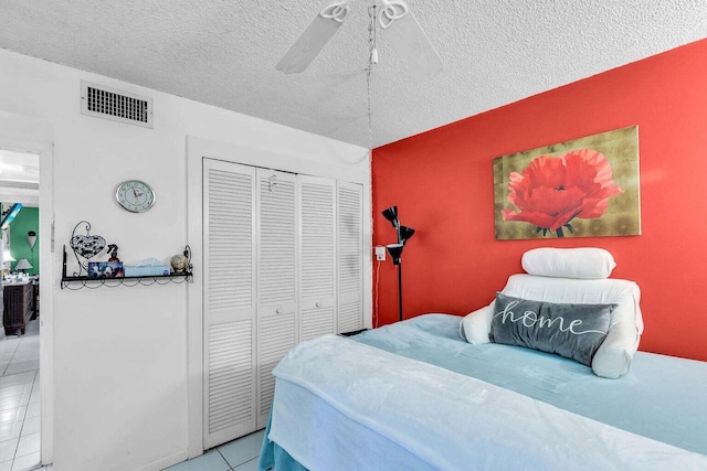 bedroom with ceiling fan, a closet, a textured ceiling, and light tile patterned flooring