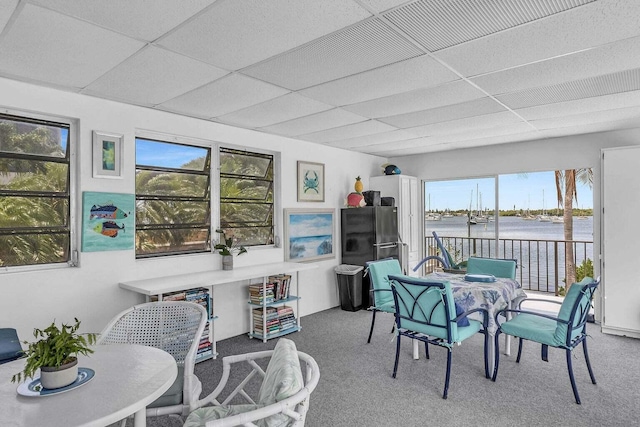 dining area featuring carpet flooring, a drop ceiling, and a water view