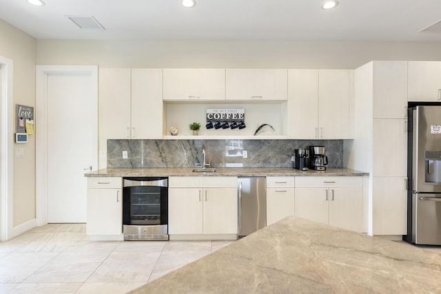 kitchen with beverage cooler, light stone countertops, stainless steel fridge with ice dispenser, a sink, and decorative backsplash