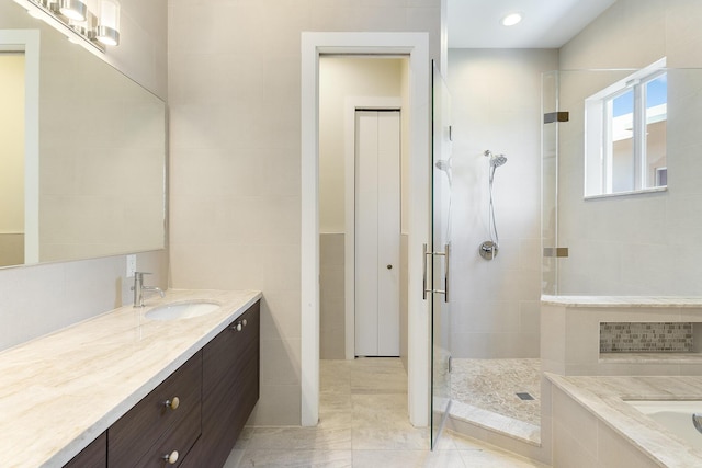 bathroom featuring tiled bath, recessed lighting, tile walls, a shower stall, and vanity