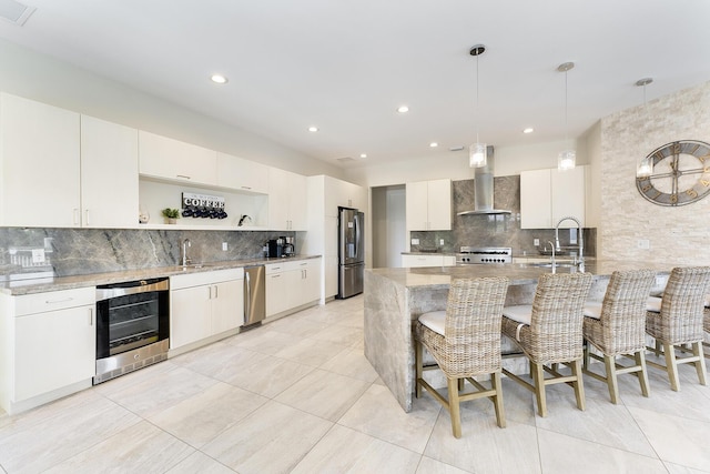 kitchen featuring a sink, wall chimney range hood, a kitchen breakfast bar, stainless steel appliances, and open shelves