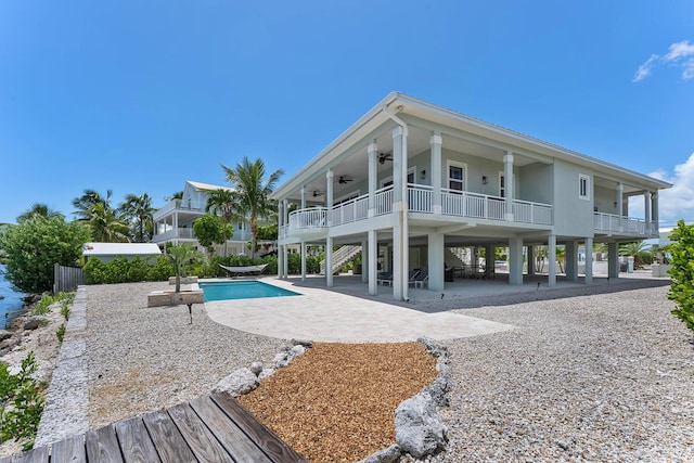 rear view of house with stairway, an outdoor pool, a ceiling fan, and a patio