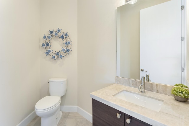 half bath with vanity, toilet, and baseboards