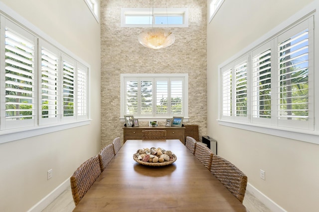 dining room featuring baseboards and a towering ceiling