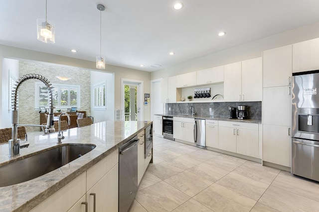 kitchen with a sink, open shelves, decorative light fixtures, tasteful backsplash, and appliances with stainless steel finishes