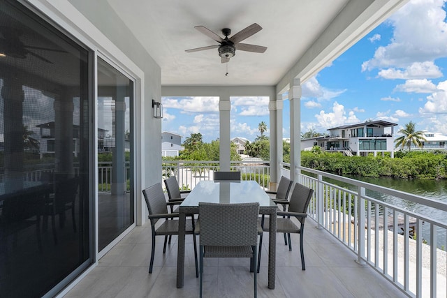 balcony featuring outdoor dining space, ceiling fan, and a water view