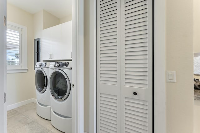 washroom featuring baseboards, cabinet space, and independent washer and dryer