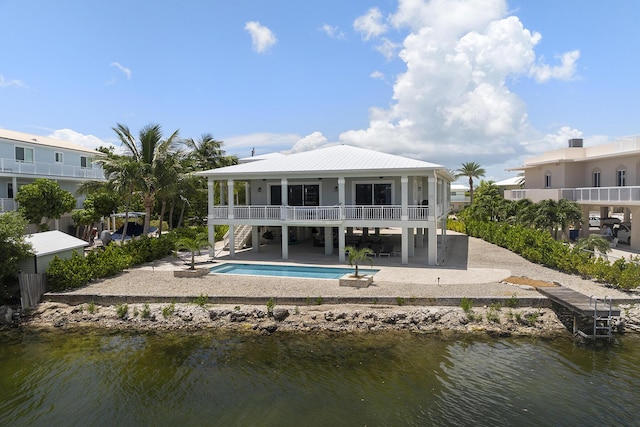 back of house featuring a water view, stairs, metal roof, a patio area, and an outdoor pool