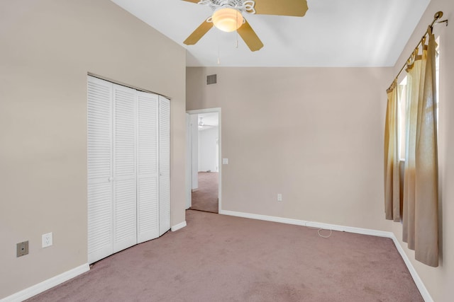 unfurnished bedroom featuring carpet floors, lofted ceiling, a closet, visible vents, and baseboards