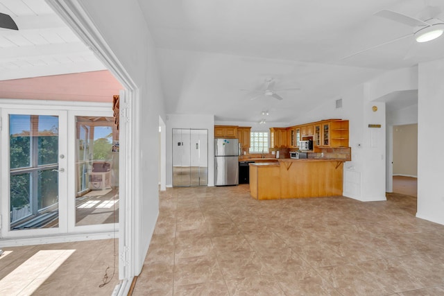 kitchen featuring a peninsula, appliances with stainless steel finishes, a ceiling fan, and lofted ceiling