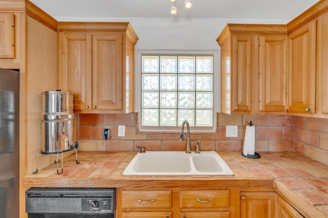 kitchen featuring a sink, decorative backsplash, tile counters, freestanding refrigerator, and dishwasher