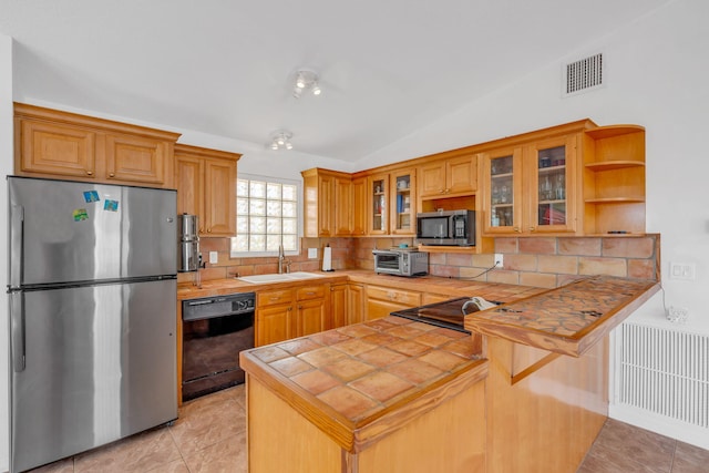 kitchen featuring tile countertops, visible vents, appliances with stainless steel finishes, a sink, and a peninsula