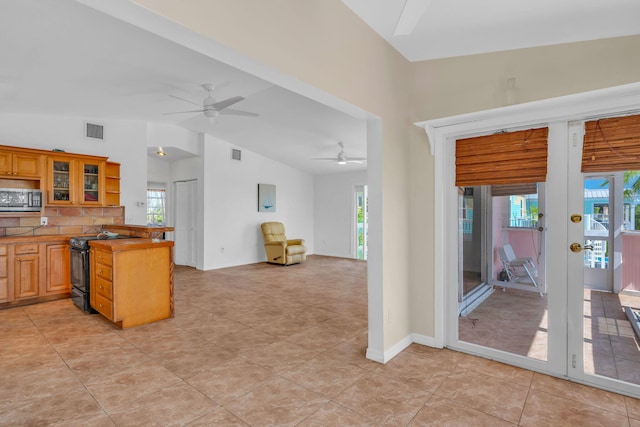 kitchen featuring lofted ceiling, black range with electric cooktop, visible vents, a wealth of natural light, and stainless steel microwave