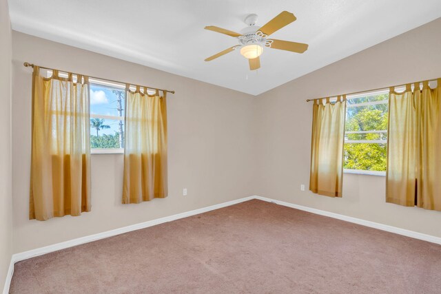 carpeted empty room featuring vaulted ceiling, ceiling fan, a wealth of natural light, and baseboards