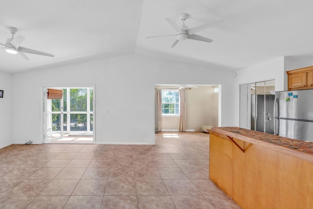 kitchen with freestanding refrigerator, vaulted ceiling, ceiling fan, and light tile patterned floors