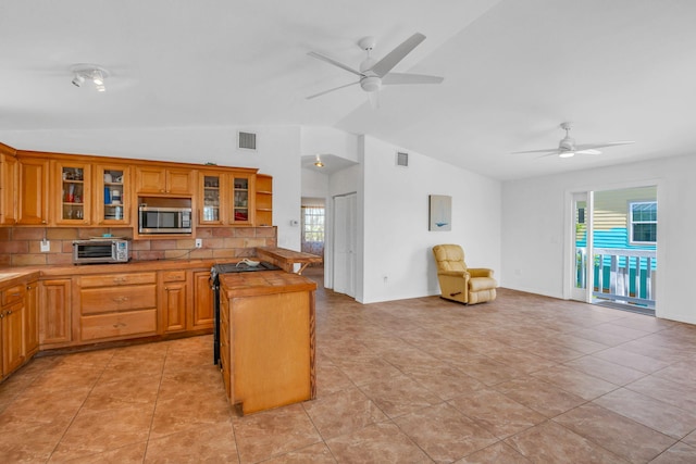 kitchen featuring a toaster, lofted ceiling, visible vents, stainless steel microwave, and open floor plan