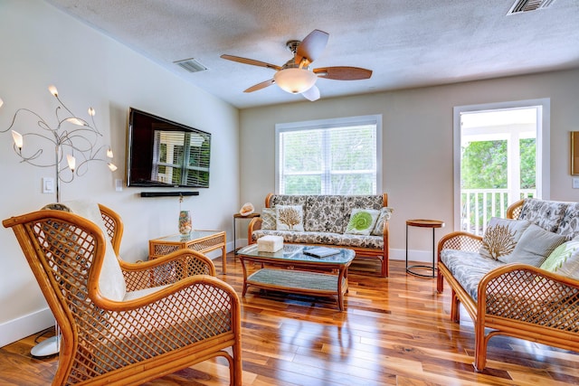 living room with ceiling fan, plenty of natural light, a textured ceiling, and light wood-type flooring