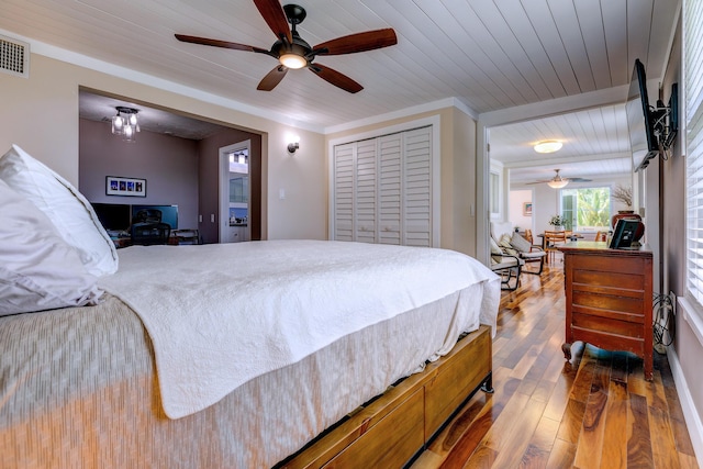 bedroom featuring wood ceiling, crown molding, wood-type flooring, a closet, and ceiling fan